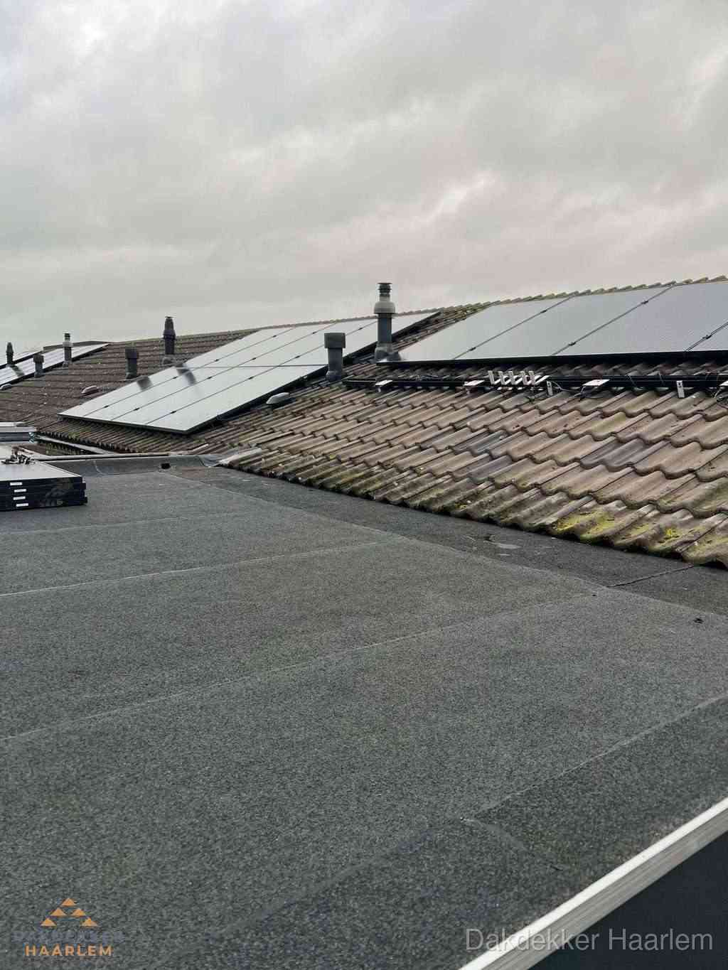 Plat dak inspectie met bitumen bedekking naast schuin pannendak in Haarlem