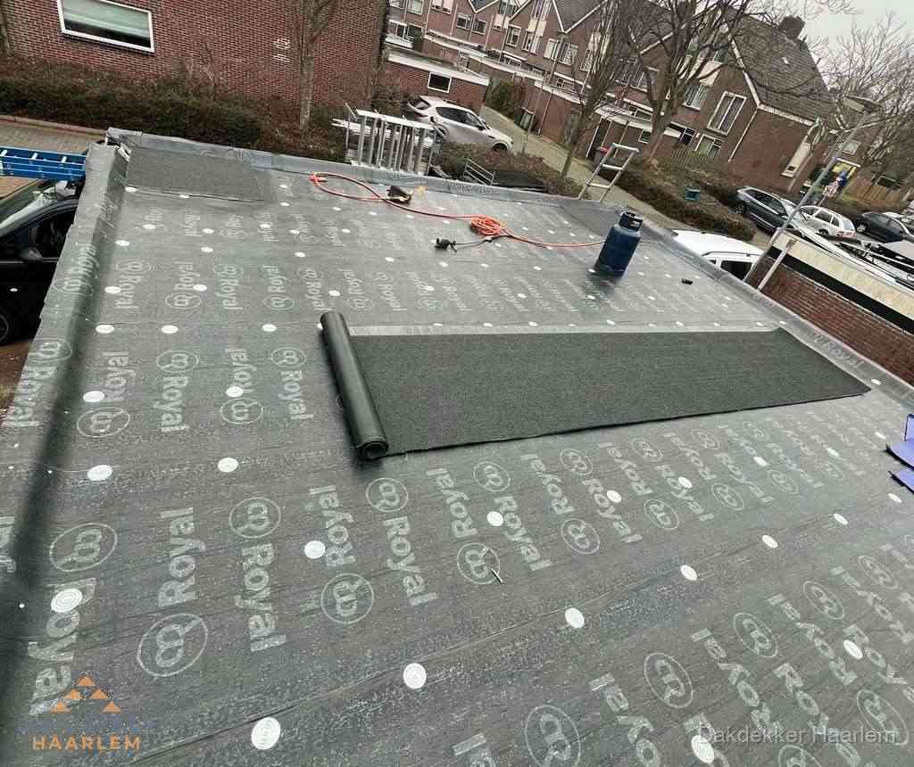 Dakdekker aan het werk met gasbrander op plat bitumen dak in Haarlem