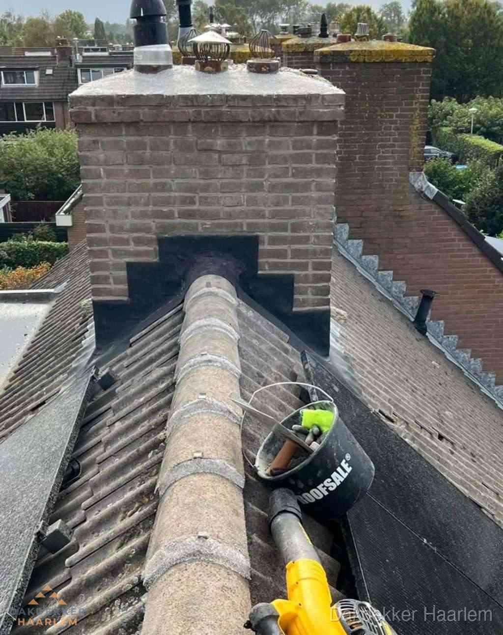 Dakdekker repareert bitumen dakleer bij dakdoorvoer in Haarlem